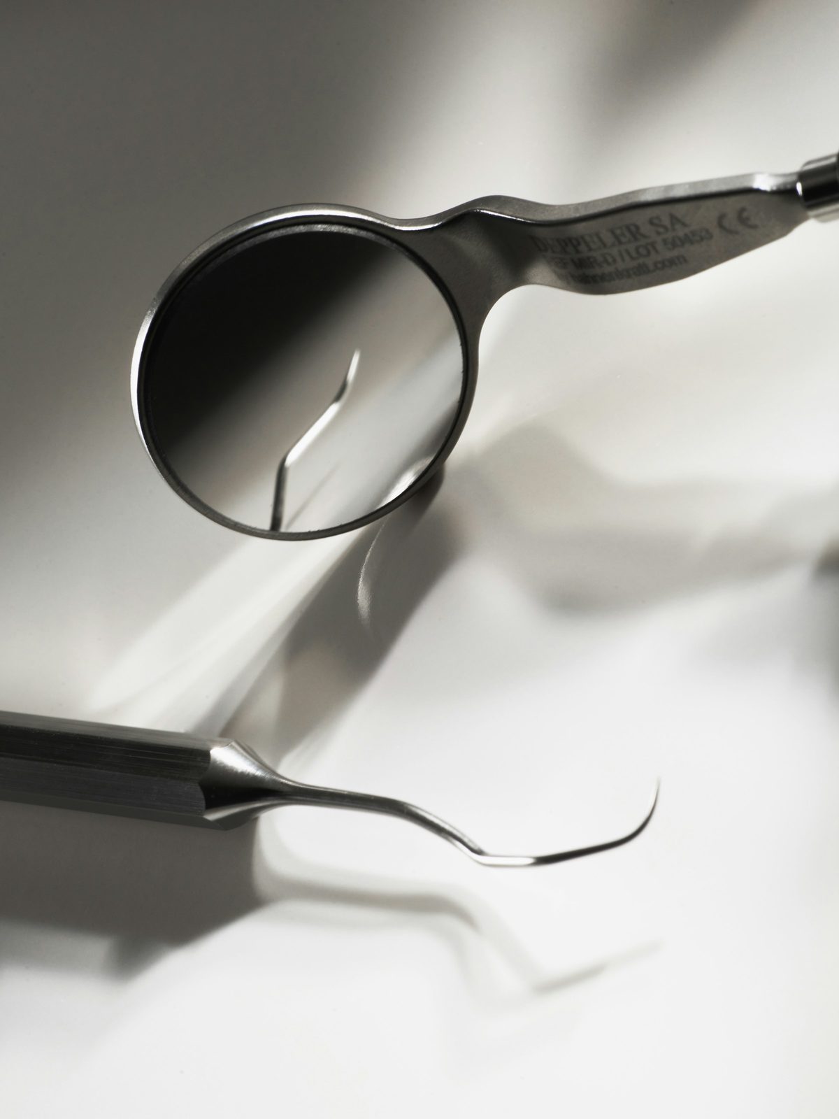 Close-up of a dental mirror and explorer on a clean white surface
