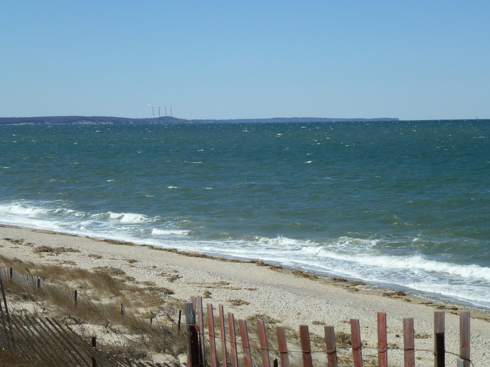 Quiet sandy beach with dune fencing along the blue waters of Long Island Sound